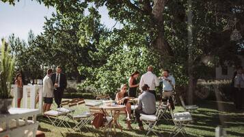 An outdoor gathering with people seated at tables under trees.
