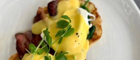 A plate with a dish that includes poached eggs, greens, and bacon.