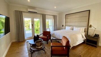 Habitación de hotel con una cama grande, un escritorio, una silla, una mesita con una taza y un televisor.