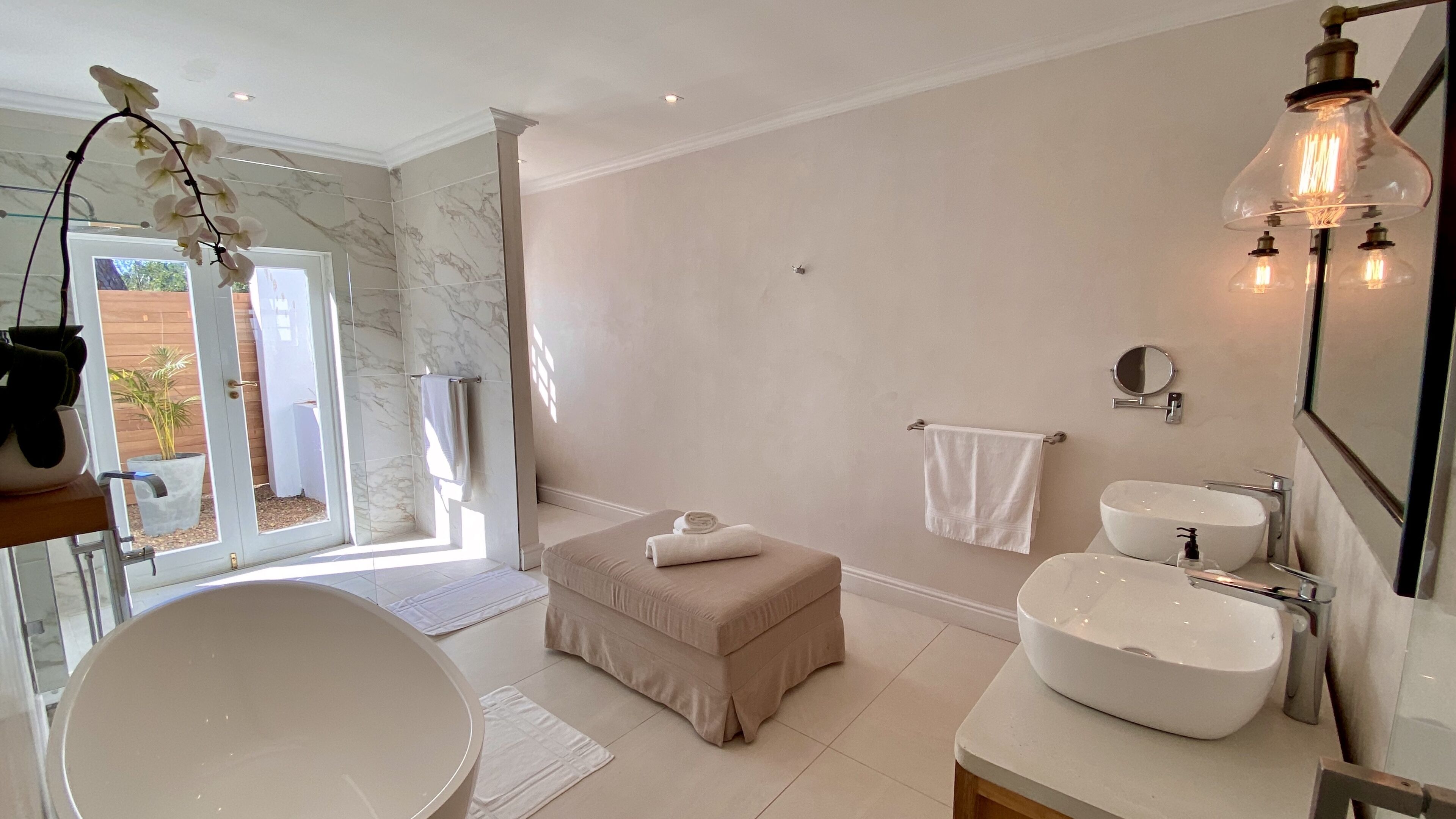 A modern bathroom with a large bathtub, a round sink, and a walk-in shower.