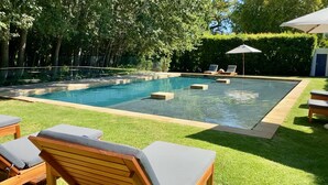 A rectangular swimming pool with a tiled edge, surrounded by a well-maintained lawn and wooden lounge chairs. - La Paris Estate (Franschhoek)