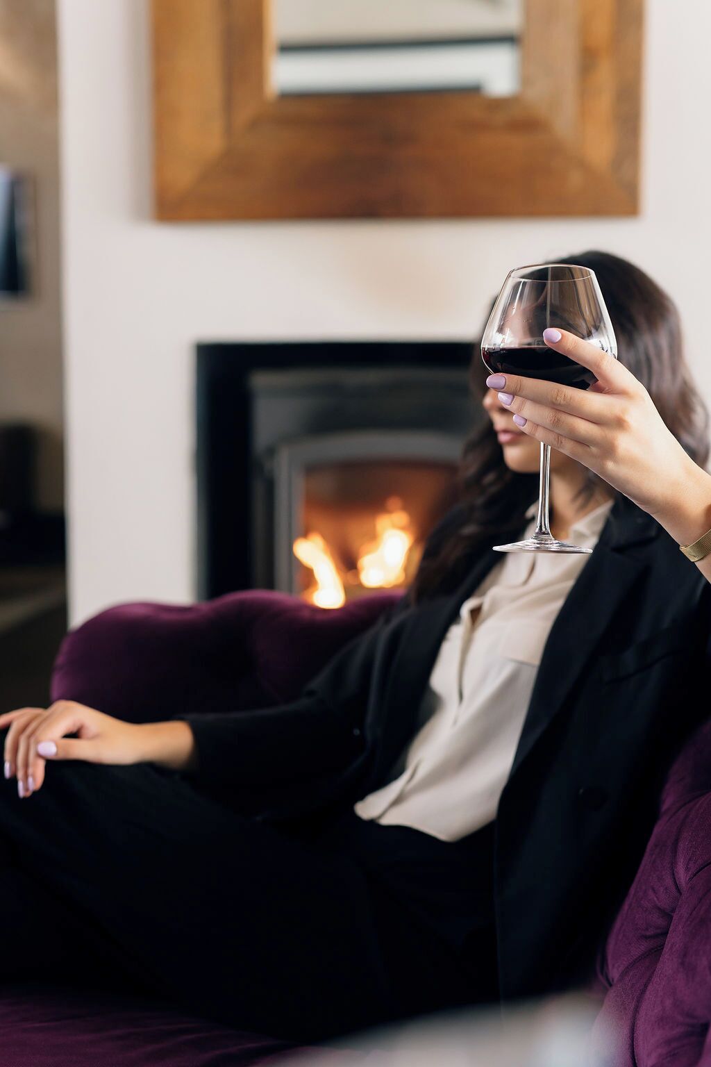 A person sitting on a purple couch in a room with a fireplace.