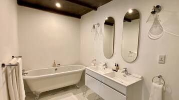 A bathroom with a freestanding bathtub, two sinks, and three mirrors.