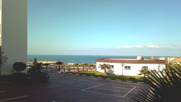 A parking lot with a view of the ocean and a building with a red roof. - Ocean Atlantic Residence 3050 (Asilah)