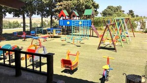 Une aire de jeux dotée de diverses installations, notamment des toboggans, des balançoires et des structures d’escalade.