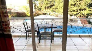 Un balcon donnant sur une piscine, avec une table et deux chaises.