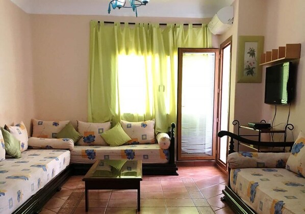 Una sala de estar acogedora con un conjunto de sofás, una mesita de centro y un televisor.