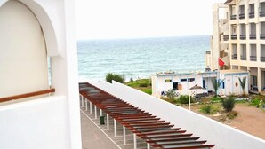 A coastal hotel with a long corridor leading to the beach, featuring a row of wooden benches and a view of the sea. - Residence Marina Beach Mdiq 3404 (Mdiq)