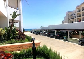 Guests can park their vehicles in the well-maintained parking area, surrounded by lush greenery and a scenic ocean view.