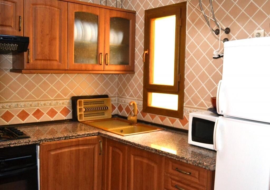 Une cuisine avec des meubles de rangement en bois, un évier, un four à micro-ondes et une fenêtre donnant sur un beau paysage.