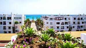 A hotel with white buildings, a central pathway, and a view of the sea. - Residence Marina Beach Mdiq 3404 (Mdiq)