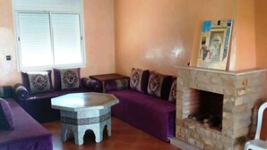 Un salon doté d’une cheminée en pierre, de canapés violets et d’une table basse en pierre.