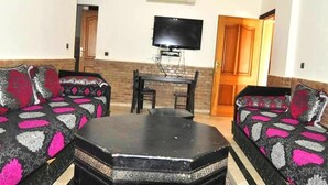 A living room with two sofas, a coffee table, a TV, and a door. - Residence Babylon Marrakech 3418 (Marrakech)