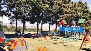 Ein Spielplatz mit verschiedenen Spielgeräten, darunter Rutschen, Schaukeln und Kletterbereiche.