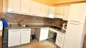 Una cocina con alacenas blancas, encimera de granito, un lavaplatos, estufa y refrigerador.
