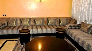 Una sala de estar con un juego de sofá, una mesa de centro y una lámpara fijada a la pared.