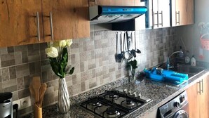 A kitchen with wooden cabinets, a gas stove, a built-in oven, and a microwave. - Lilac's Garden Residence 2947 (Cabo Negro)