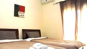 Una habitación de hotel con dos camas, un cuadro en la pared y una ventana con cortinas.