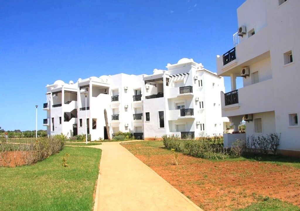 A modern apartment complex with multiple balconies, a central pathway, and a well-maintained lawn.