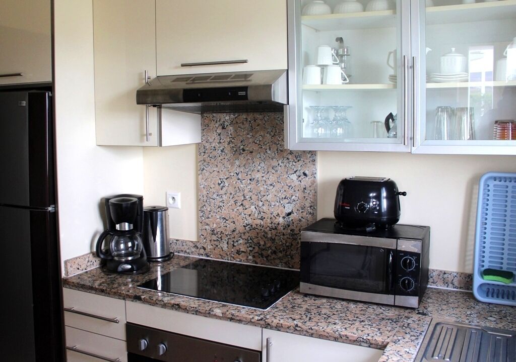 A compact kitchen with a granite countertop, a microwave, a toaster, and a coffee maker.