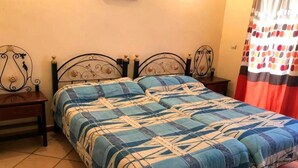 Ein Zimmer mit einem Bett, zwei Nachttischen, einem Wandbild und einem Vorhang mit Punkte-Muster.