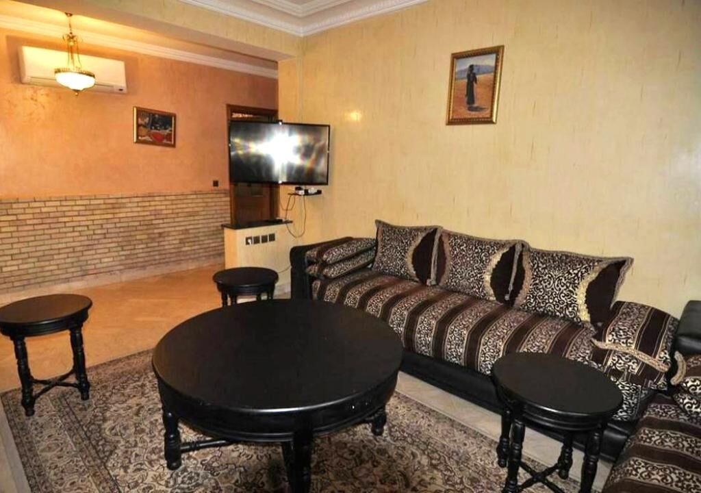 A living room with a sofa, two round tables, a flat-screen TV, and a fireplace.