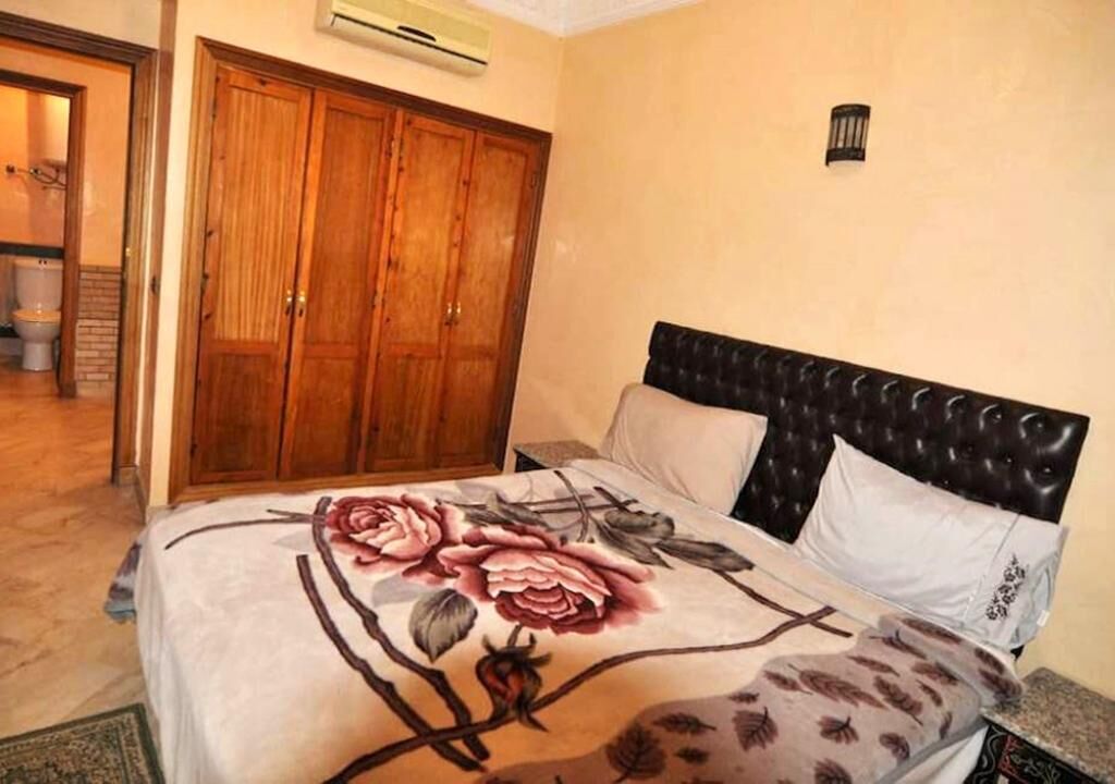 Une chambre à coucher avec un lit, une armoire en bois et une table de chevet.