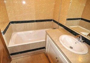 Un baño con bañera, lavamanos y espejo.