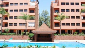 Ein Hotel mit einem zentral gelegenen Pool, umgeben von Palmen und einem kleinen Pavillon.