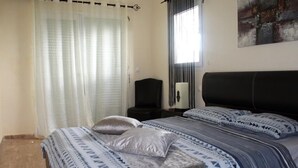 Una camera da letto con un letto, un comodino, una lampada e una finestra con tende.
