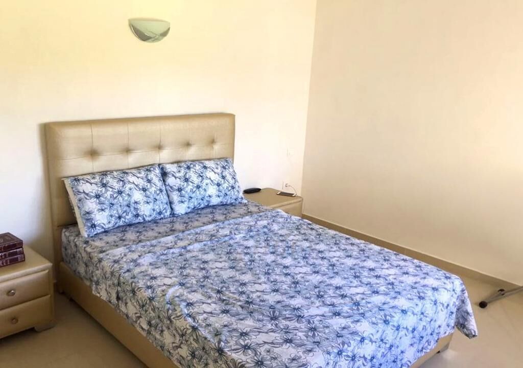 Ein Schlafzimmer mit einem Bett, einem Nachttisch und einer Wandleuchte.