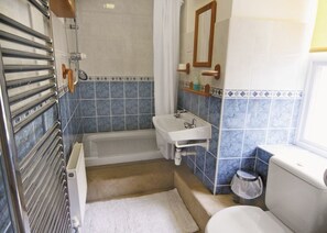 Bathroom features a shower, sink, and toilet, with a glass door and a tiled wall.