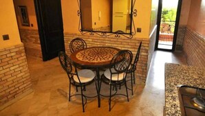 A dining area with a round table and chairs, a large mirror above the table, and a view of the outdoors through a door. - Residence Barrone Marrakech 3384 (Marrakech)