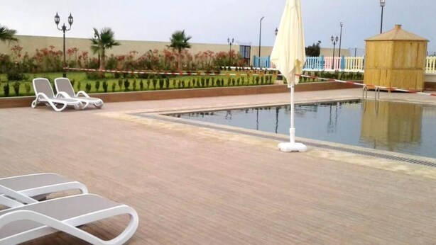 Un área de piscina con sillones de descanso y una sombrilla.