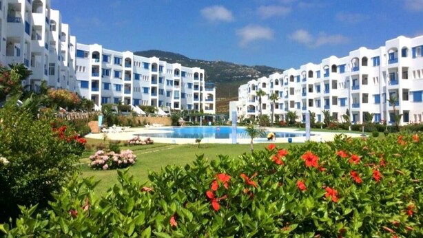 A resort with white buildings, a swimming pool, and red flowers. - Residence Java Rasmile Mdiq 3396 (Mdiq)