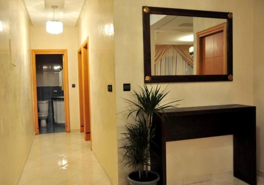 Ein Flur mit einem Blumentopf, einem Spiegel und einer Holztür, die ins Badezimmer führt.