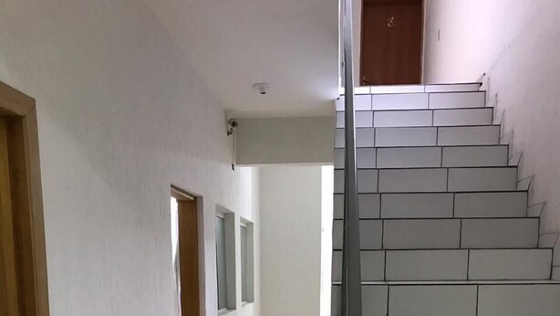 A hallway with a tiled floor leading to a staircase. - Espaço da Caraputinga (São Paulo)