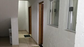 A corridor with tiled flooring, white walls, and a wooden door at the end. - Espaço da Caraputinga (São Paulo)