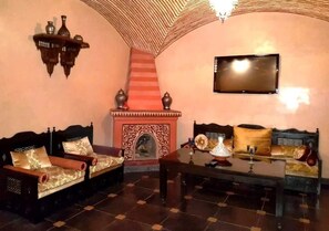 A traditional Moroccan interior with a sofa set, a fireplace, and a television mounted on the wall. - Villa Amerchich 2968 (Marrakech)