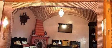 A room with a high arched ceiling, a fireplace, and two sofas.