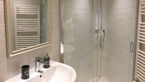 A modern bathroom with a glass-enclosed shower, a white sink with a mirror above it, and a towel rack beside the sink. - The Chiaia steps :camera white (Napoli)