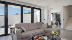 Un salon moderne avec un canapé gris, une table basse sur laquelle se trouve un panier de fruits et un vase rempli de fleurs.
