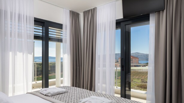 Une chambre d’hôtel avec un lit, une grande fenêtre avec des rideaux et une vue sur la campagne.
