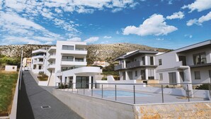 Un quartier résidentiel moderne, avec des bâtiments contemporains, une piscine et une colline en arrière-plan.