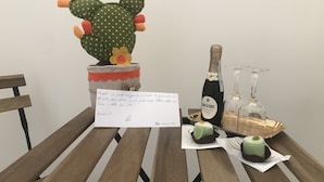 A wooden table with a cactus, a bottle of Maschio Prosecco, two wine glasses, and a small cake. - Le Camere di Don Vito (Noto)