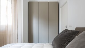 A bedroom with a bed, a wardrobe, and a window with curtains. - Design e Comfort nel centro di Catania by Wonderful Italy (Catania)