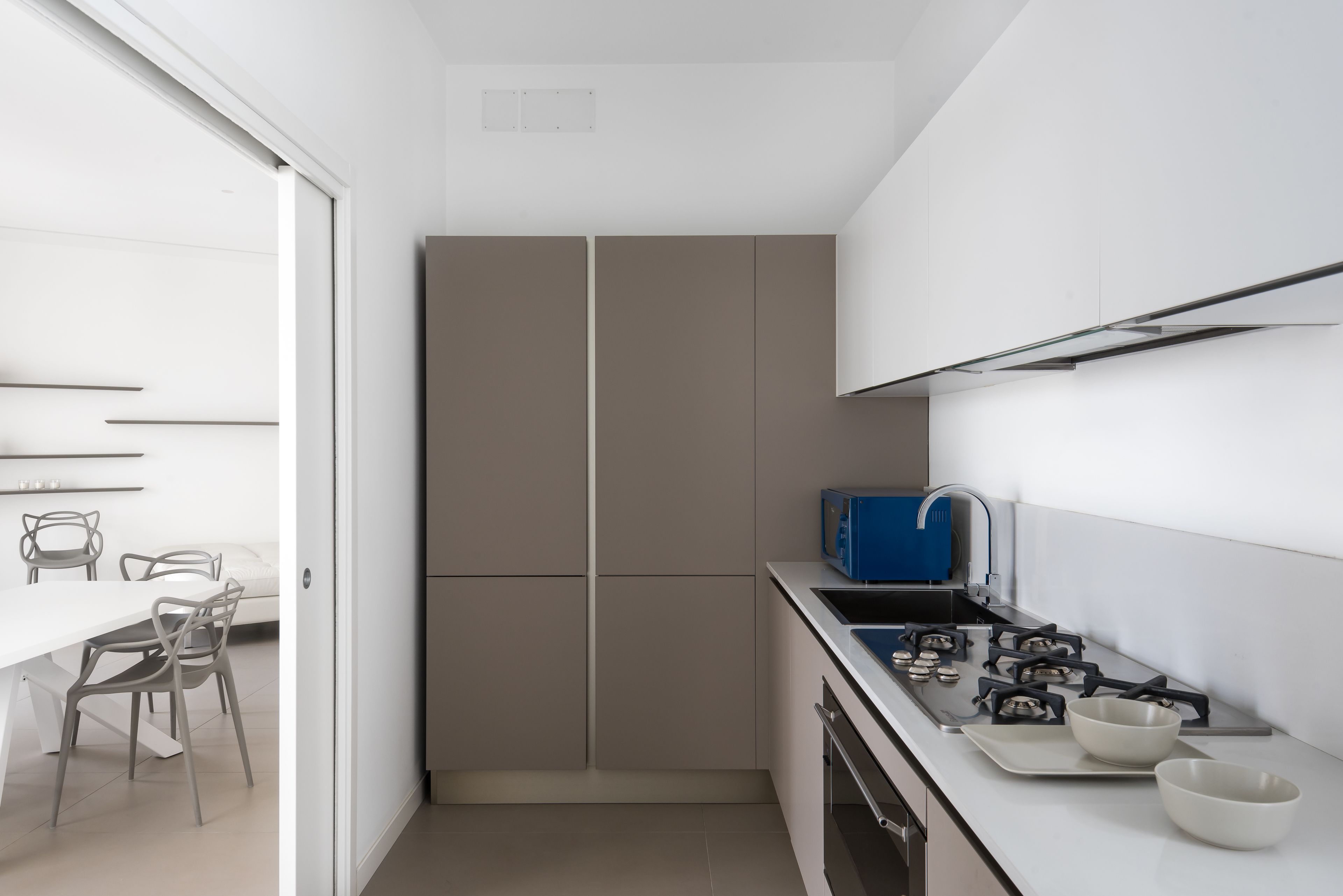 A compact kitchen with a gas stove, a sink, and a blue microwave.