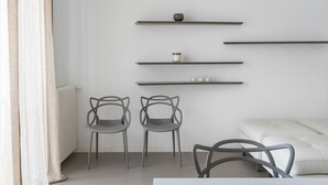 A modern living room with minimalist furniture, including two chairs and a white sofa. There are three floating shelves with decorative items and a radiator on the wall. - Design e Comfort nel centro di Catania by Wonderful Italy (Catania)
