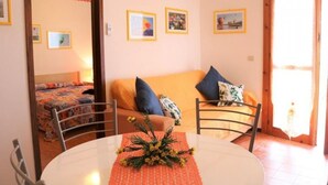 Una sala de estar acogedora con un sofá, sillas, una mesa de comedor con un centro de mesa y cuadros en la pared.
