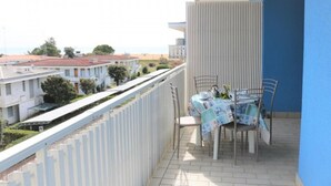 Un balcón con mesa y sillas, con vistas a una zona residencial con casas y un cielo despejado.